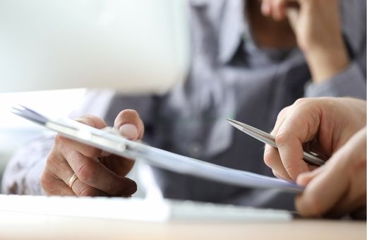 A person signing a document while the other person points out where to sign