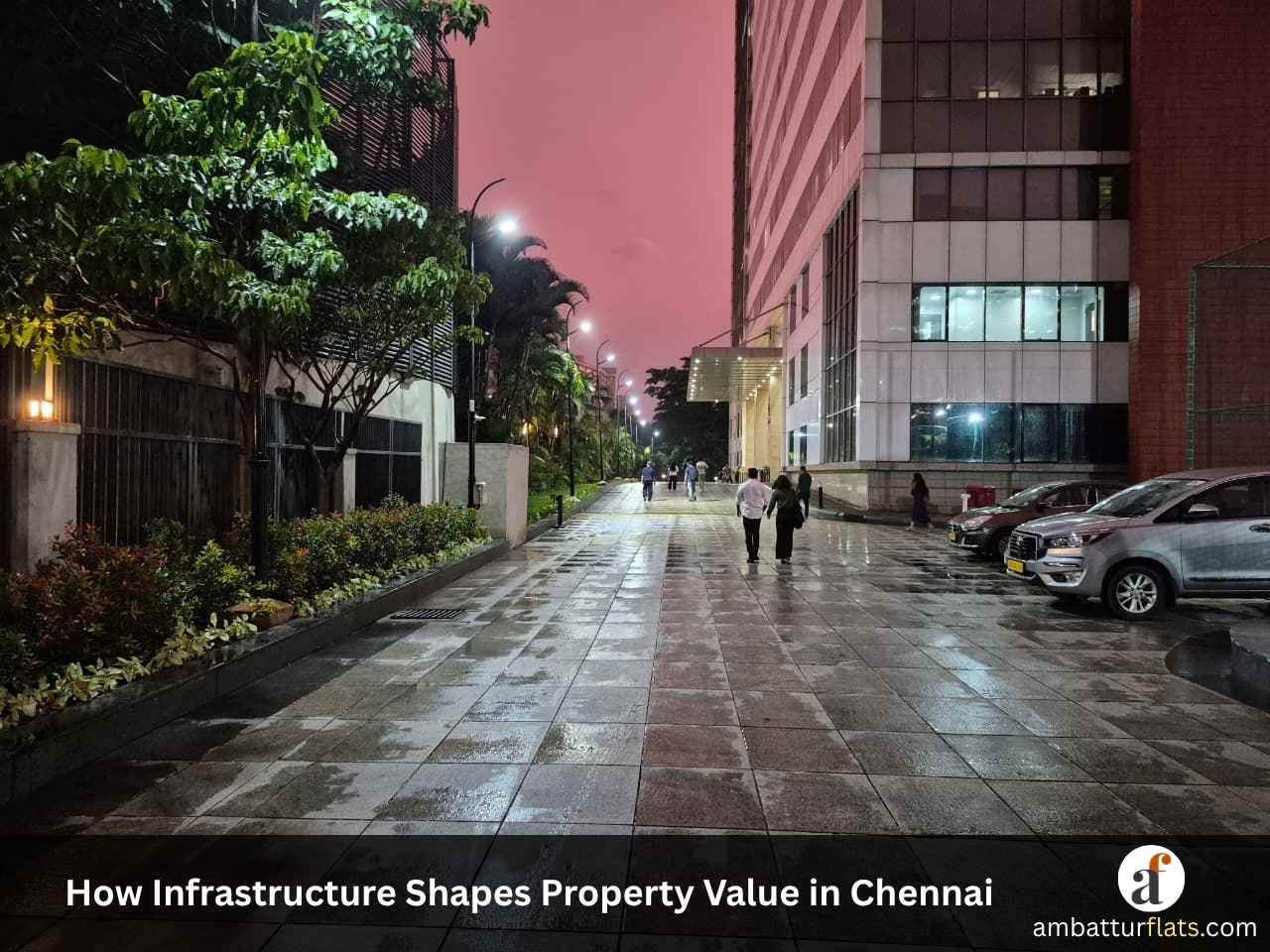 Well-lit paved street and modern buildings in Chennai after rain