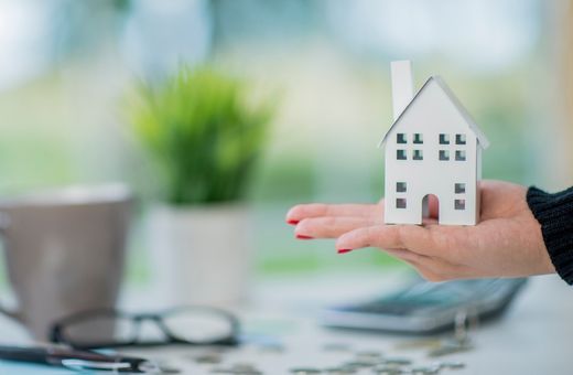 A person holding a toy house in hand
